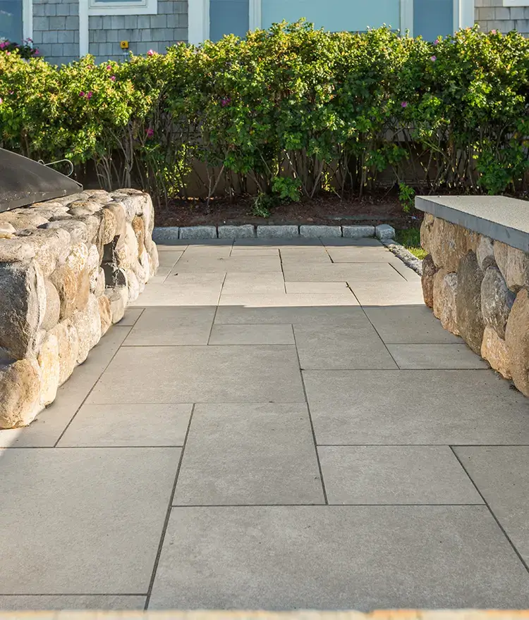 Beige Everblue Sand pavers on a patio between fieldstone walls