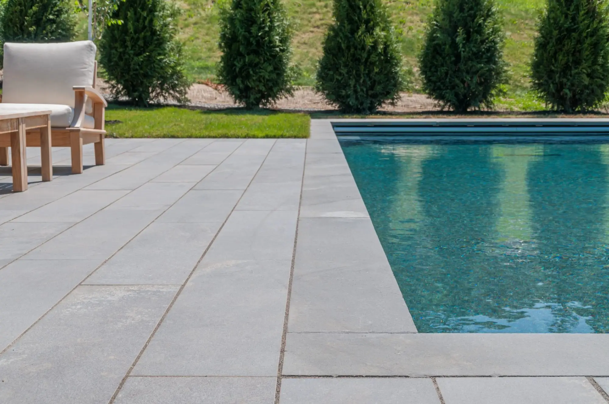 Thermal Blue Everblue pavers in a large-format running bond beside a pool
