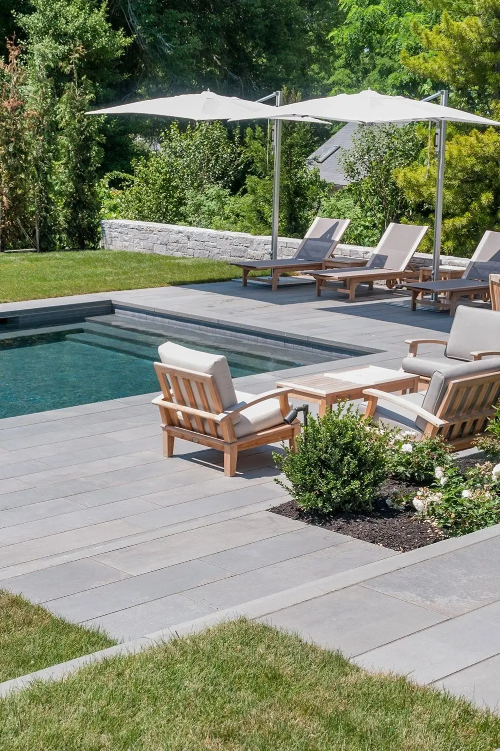 Everblue pavers around a pool with teak lounge chairs