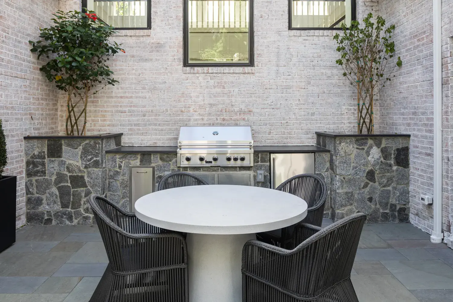 Everblue porcelain pavers in an outdoor kitchen and dining area with a stone grill surround